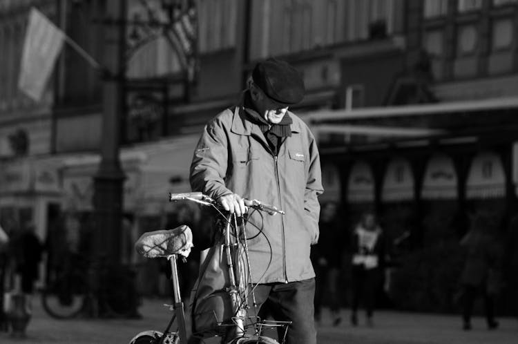 A Man Is Walking Down The Street With His Bike