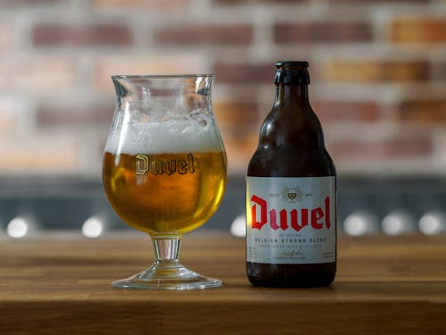 Close-up of a Bottle and Glass of Beer Standing on a Wooden Table 