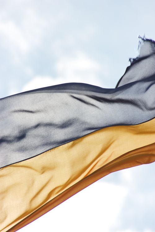 Free A Ukrainian flag gracefully waves in the wind against a clear blue sky, symbolizing national pride. Stock Photo