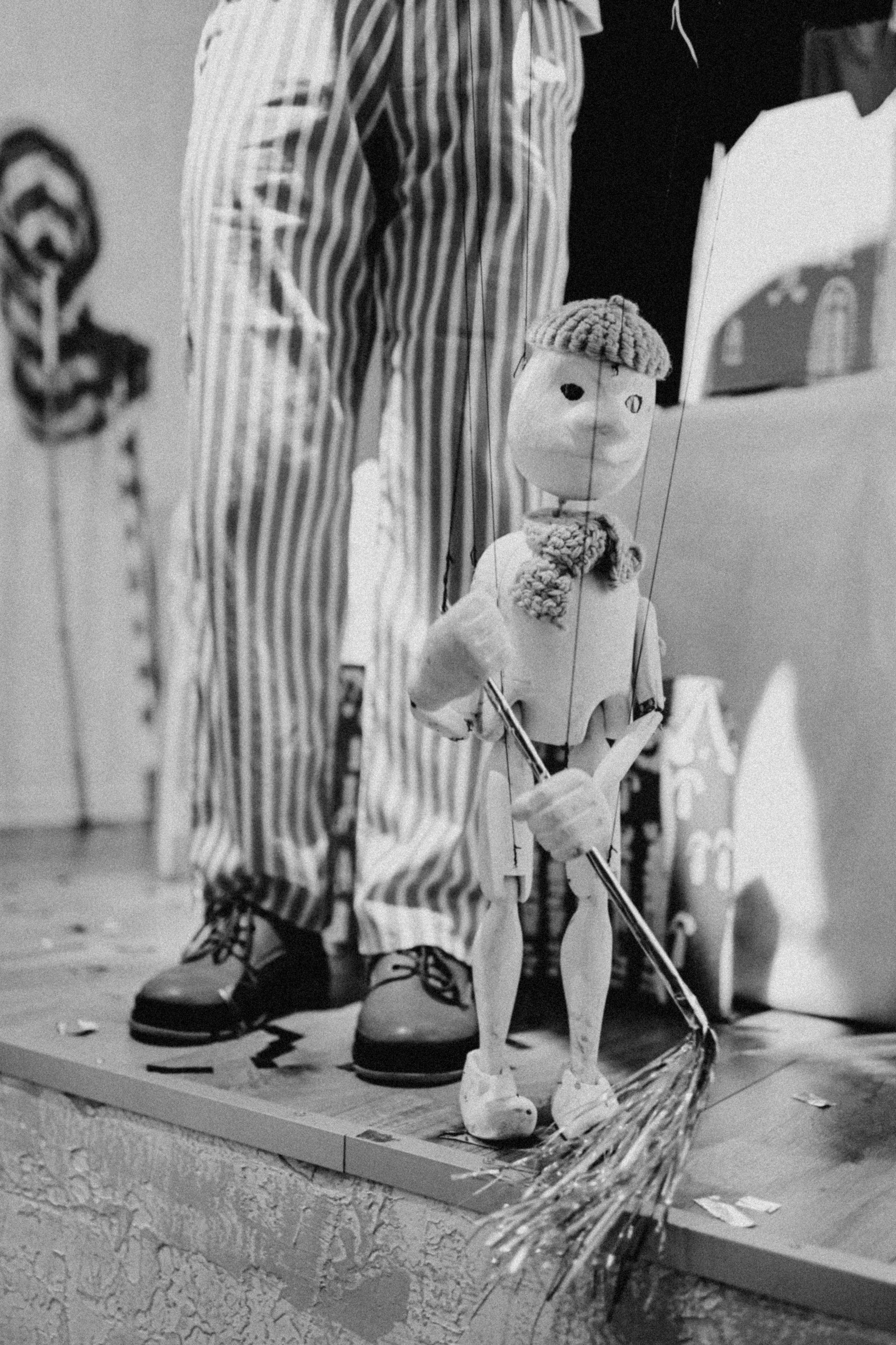 A captivating black and white image of a puppet and performer with striped pants.