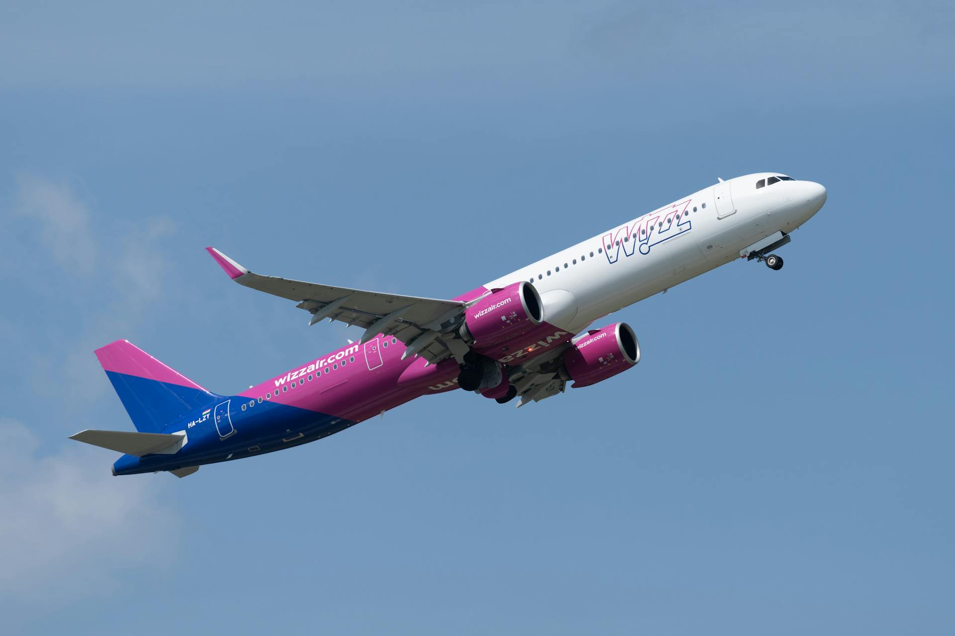 Dynamic view of Wizz Air Airbus A321 jet soaring against a blue sky.