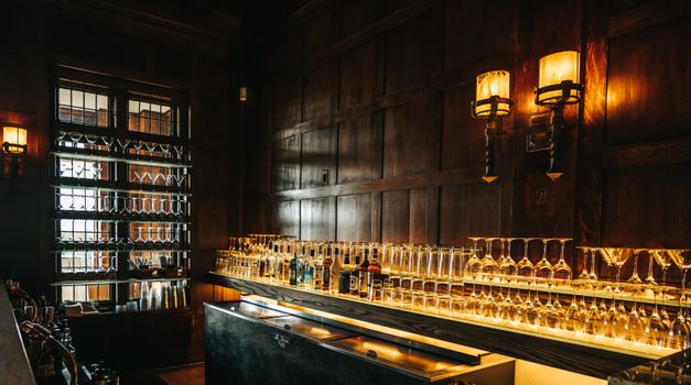 A retro-style bar interior with elegant glassware and bottles on wooden shelves, creating a warm atmosphere.