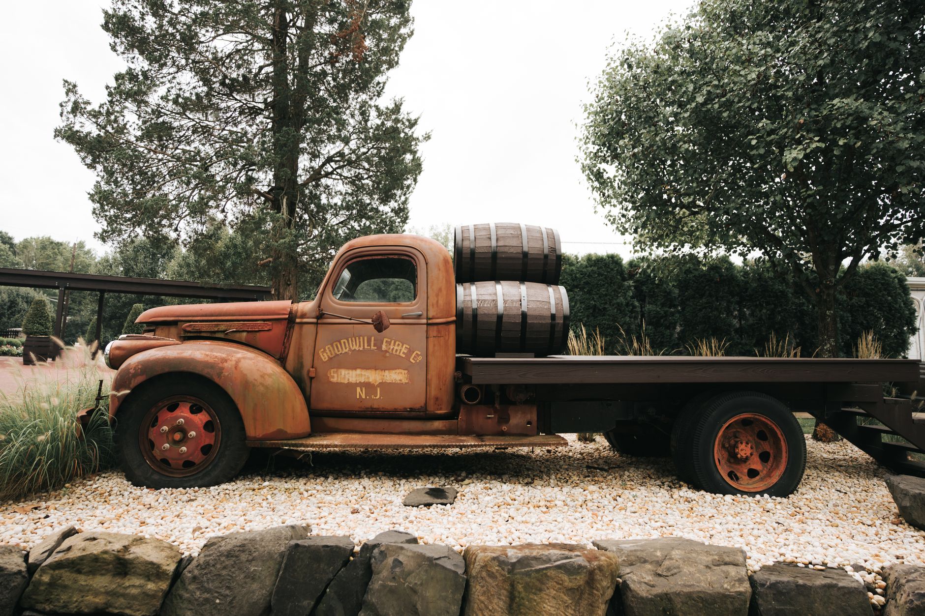 A rusty vintage truck with barrels sits parked outdoors, evoking nostalgia and rustic charm.