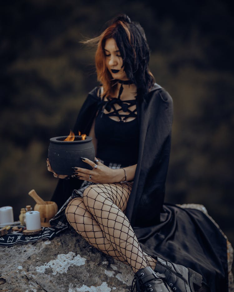 Woman In Witch Costume Holding Pot With Fire