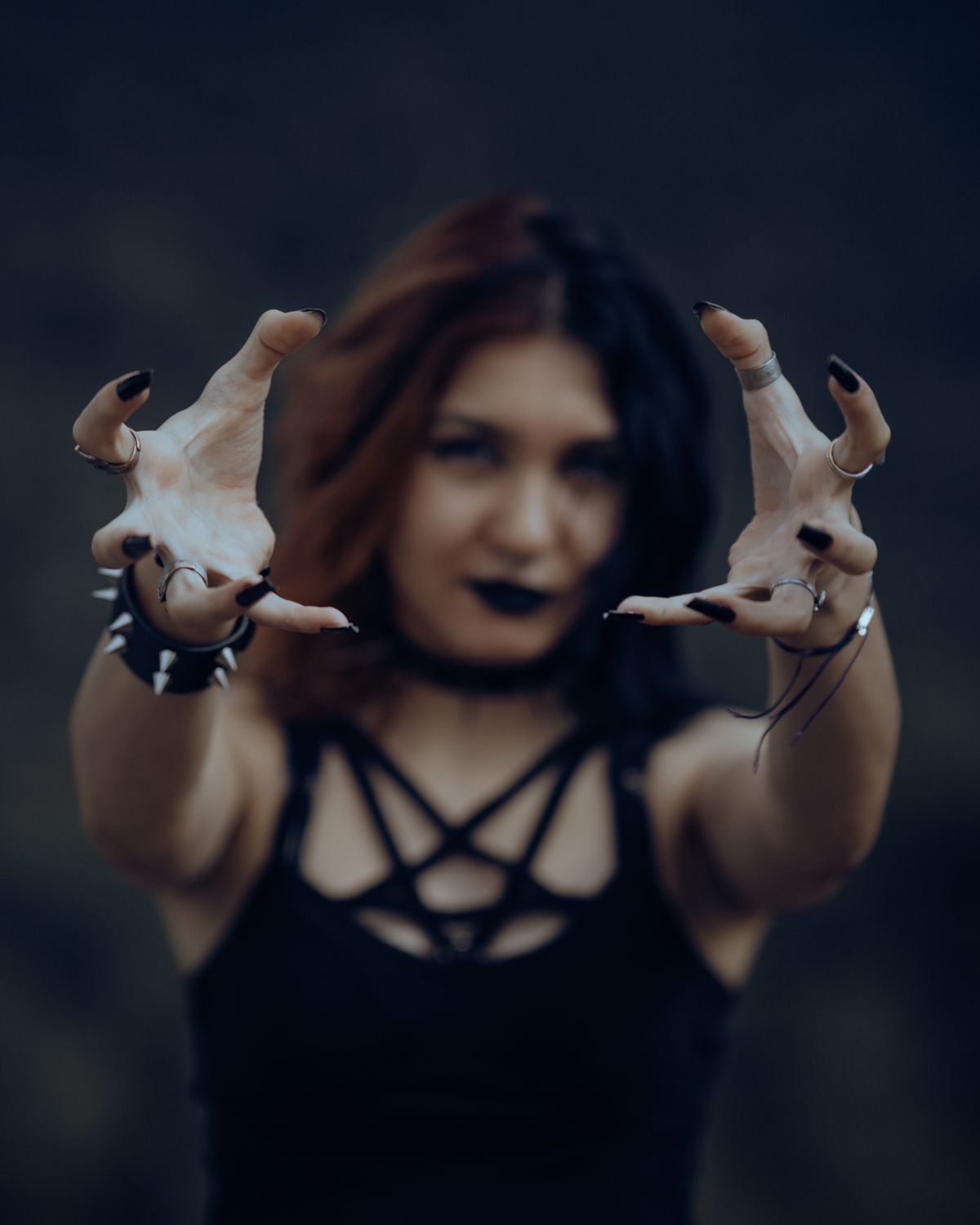 A gothic woman with dark lips and black outfit reaches forward, creating a mysterious atmosphere.