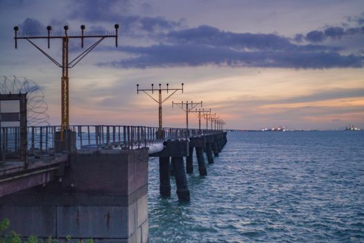 九号码头在平静的日落下，背景是柔和的海浪和城市灯光