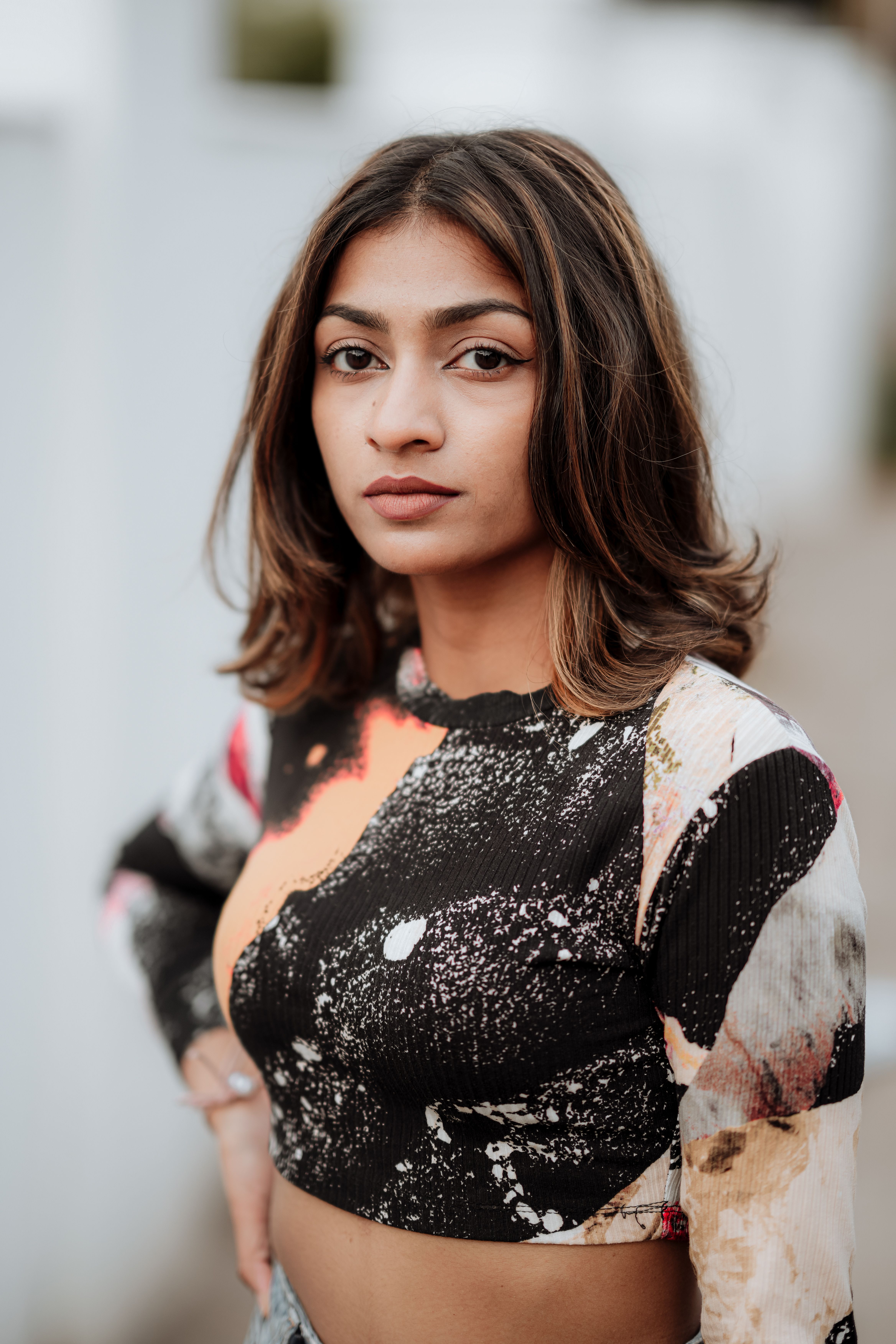 Confident woman in a colorful crop top, posing with hand on hip outdoors. Fashion photography.