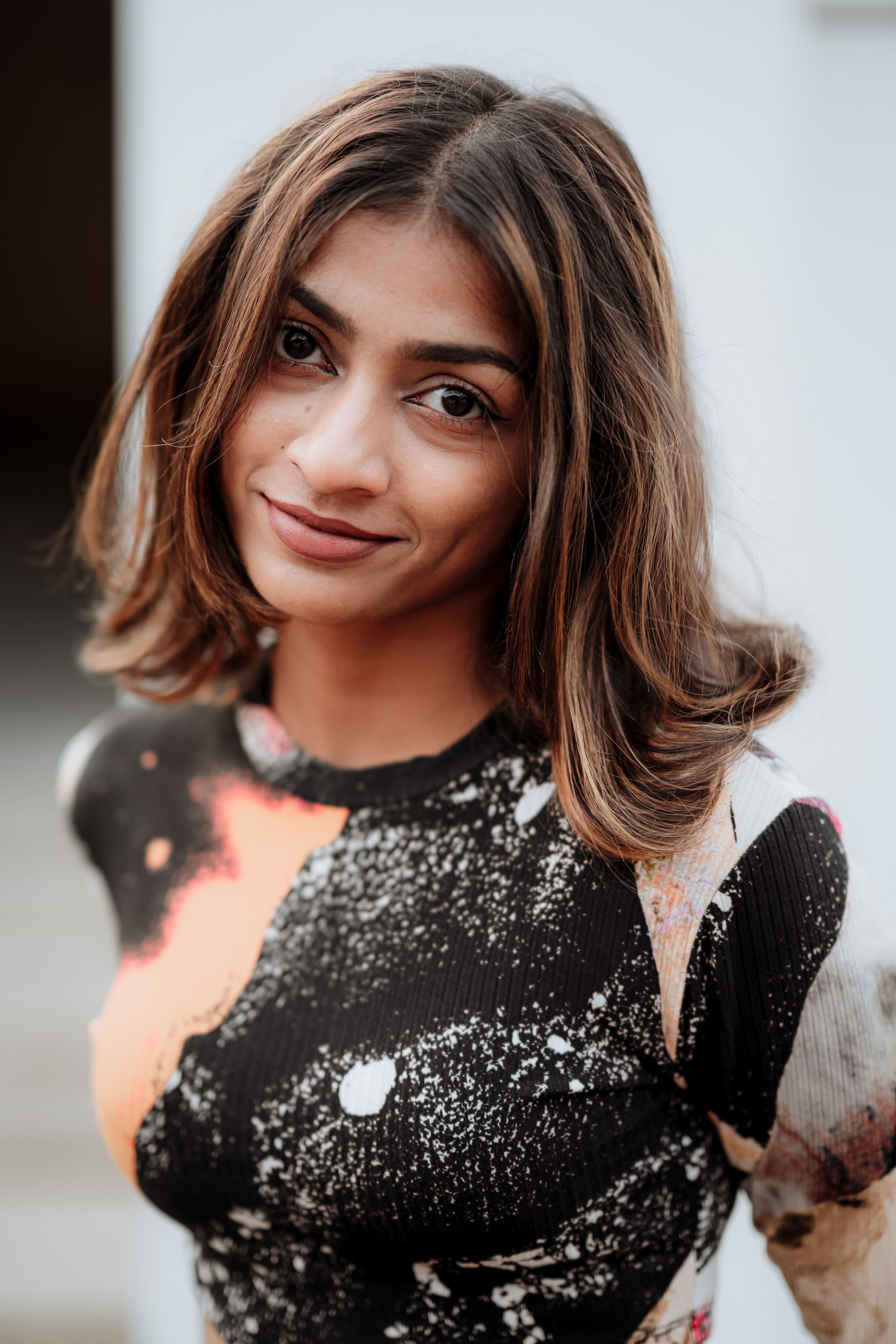 Close-up portrait of a woman posing outdoors in a multi-colored blouse, showcasing modern fashion.