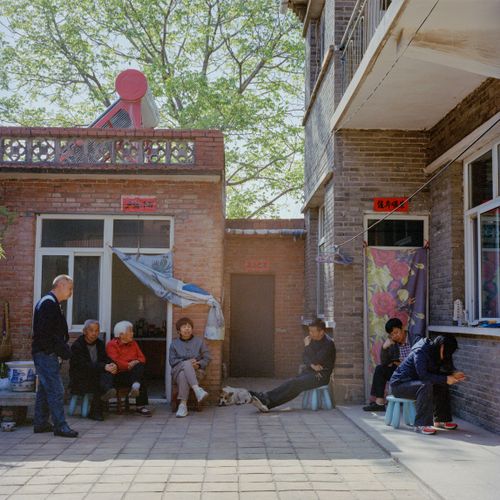 Free Group of adults sitting and talking in a sunny courtyard, enjoying leisure time. Stock Photo