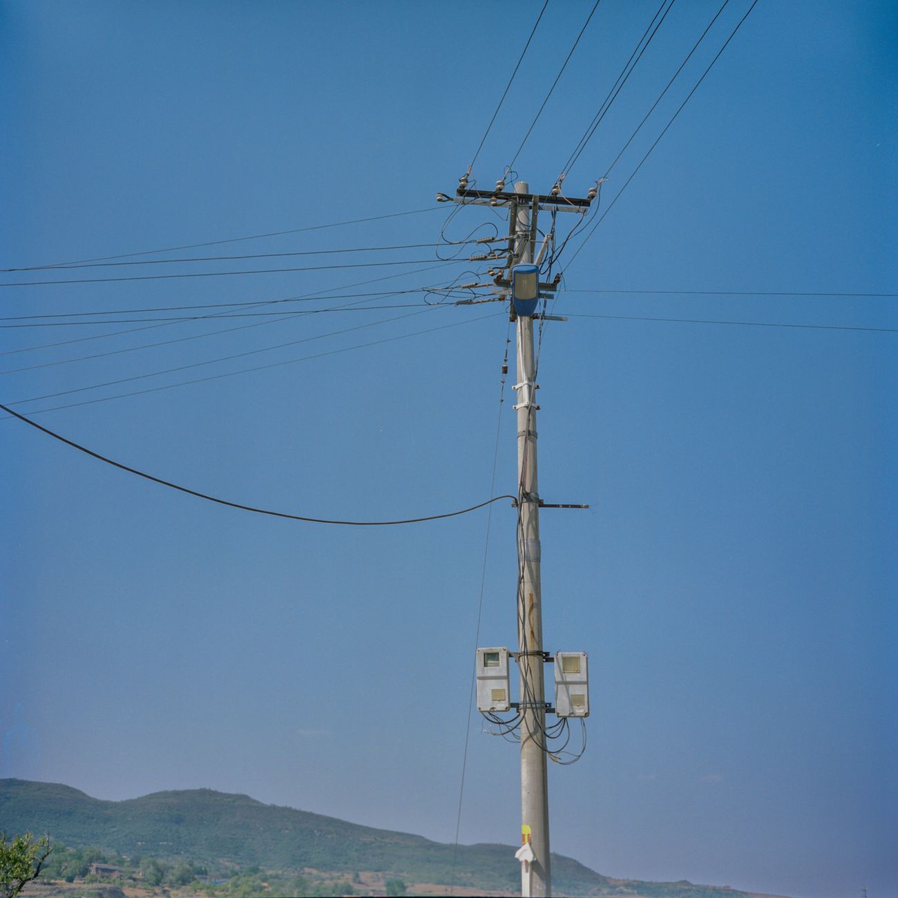 A vertical shot of a power transmission pole with cables under a clear blue sky, emphasizing energy.