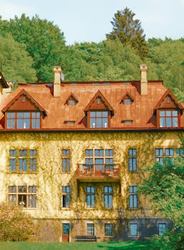 Elegant mansion facade with rustic charm framed by vibrant greenery.