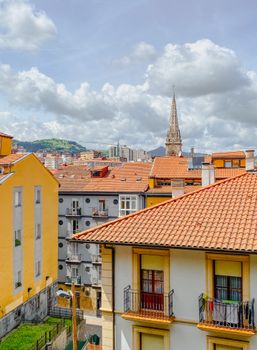 Charming view of Bilbao's cityscape with a historic tower under a bright sky, showcasing urban architecture.