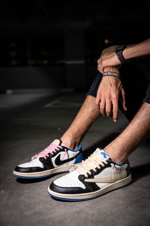 Free Close-up of stylish sneakers and hands, sitting in a dark urban environment, perfect for modern fashion. Stock Photo