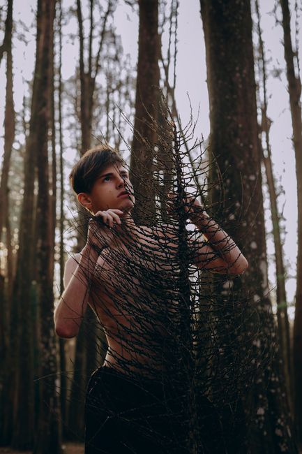 Artistic portrait of a shirtless man in a forest setting during fall, emphasizing mood and nature.