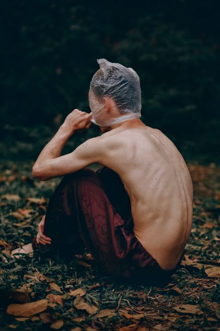 A dramatic outdoor portrait of a contemplative figure wrapped in deep thought, evoking mystery.