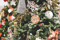 一棵装饰精美的圣诞树特写，上面挂着节日装饰品和圣诞快乐标志