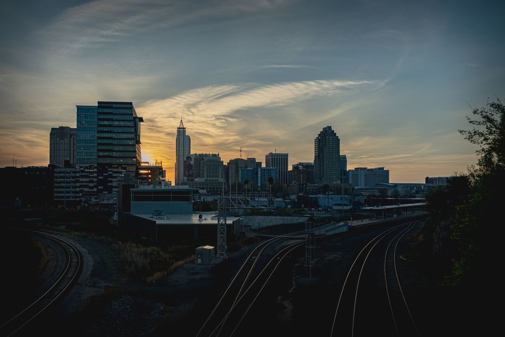 The downtown Raleigh skyline at sunset, seen across the rail corridor