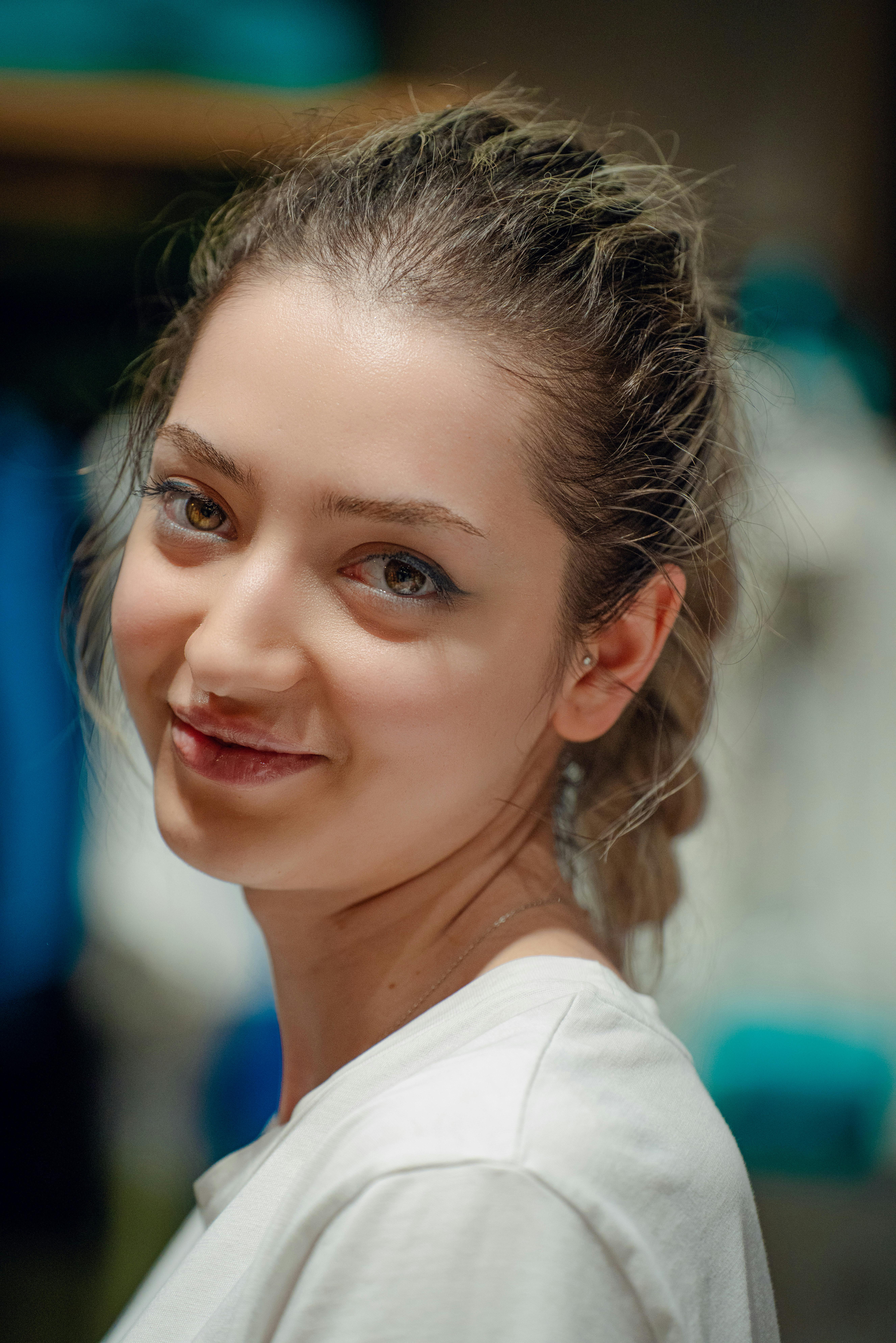 A beautiful young woman with a bright smile wearing a white t-shirt, photographed indoors.