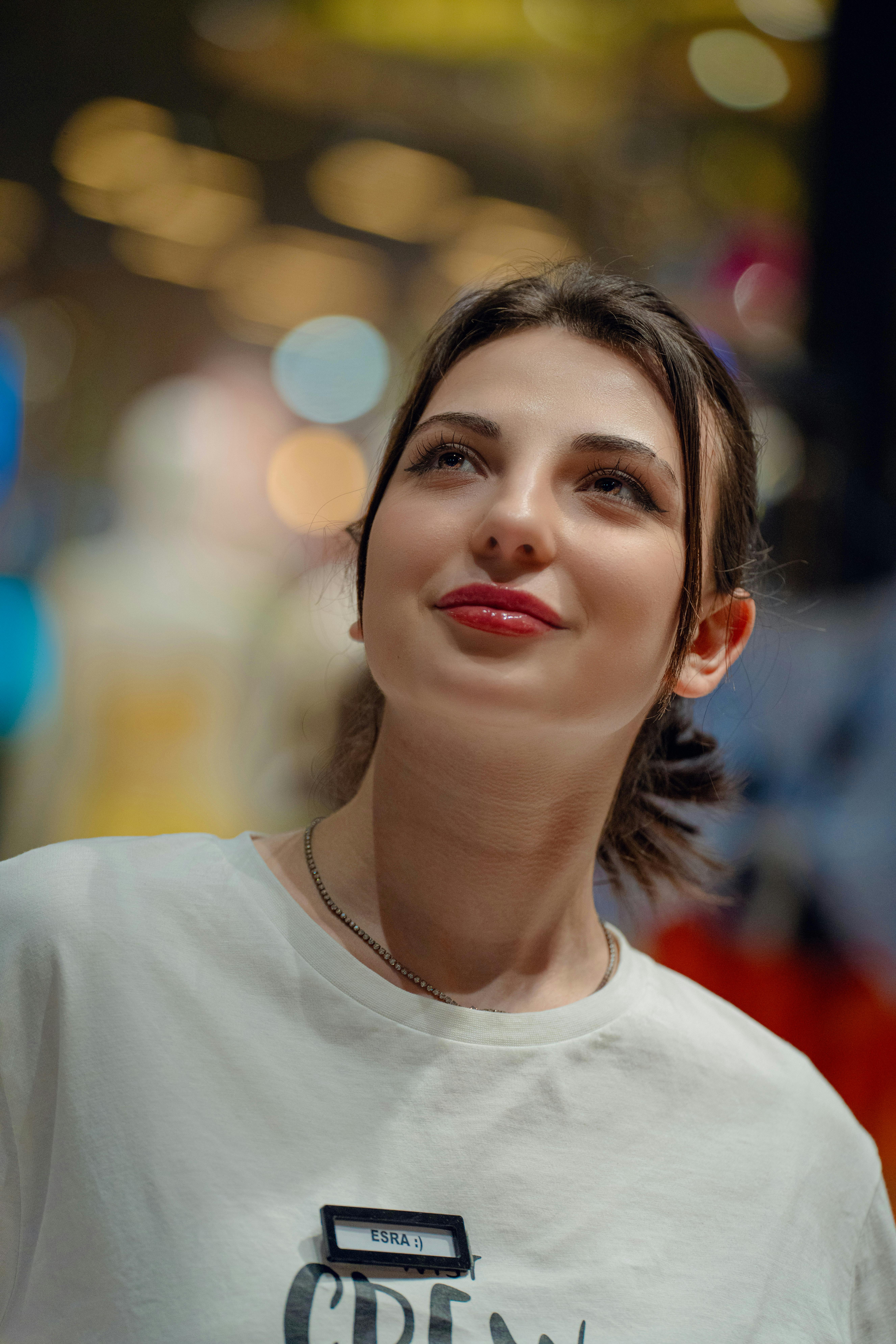 A smiling woman looks up surrounded by colorful bokeh lights in an Istanbul mall.