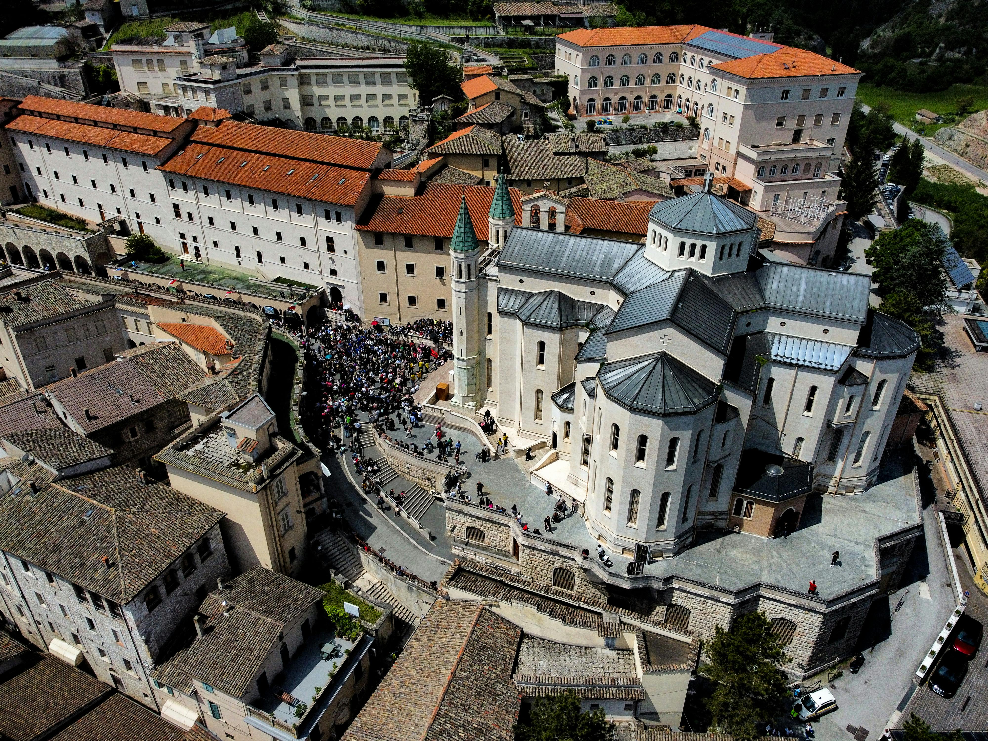 Aerial photograph of a monastery and crowd in Umbria, Italy, showcasing historical architecture.