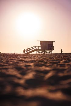 A serene sunset view at Santa Monica Beach, highlighting a lifeguard tower silhouetted against the vibrant sky.
