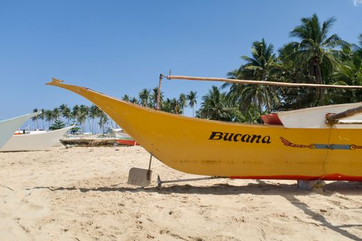 Yellow jukung boat on sandy beach with palm trees, sunny day in Bali. - Fotografer Sidoarjo