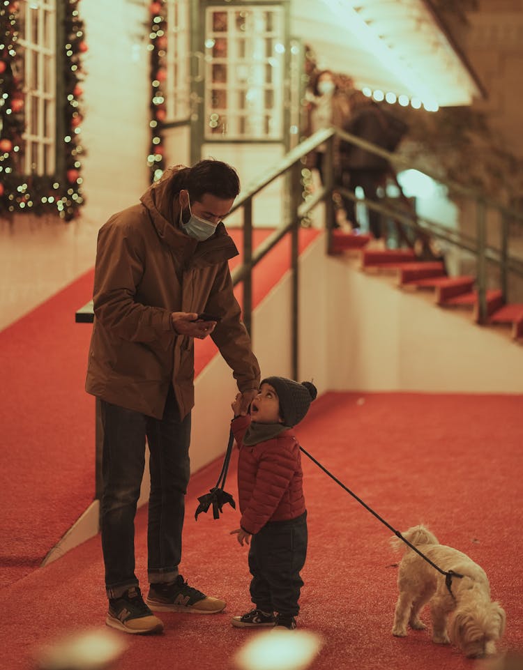 Man With Child And Dog On Leash Standing By Entrance To House