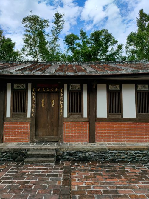 Free Charming traditional Chinese building with brick facade and decorative script, surrounded by lush greenery. Stock Photo