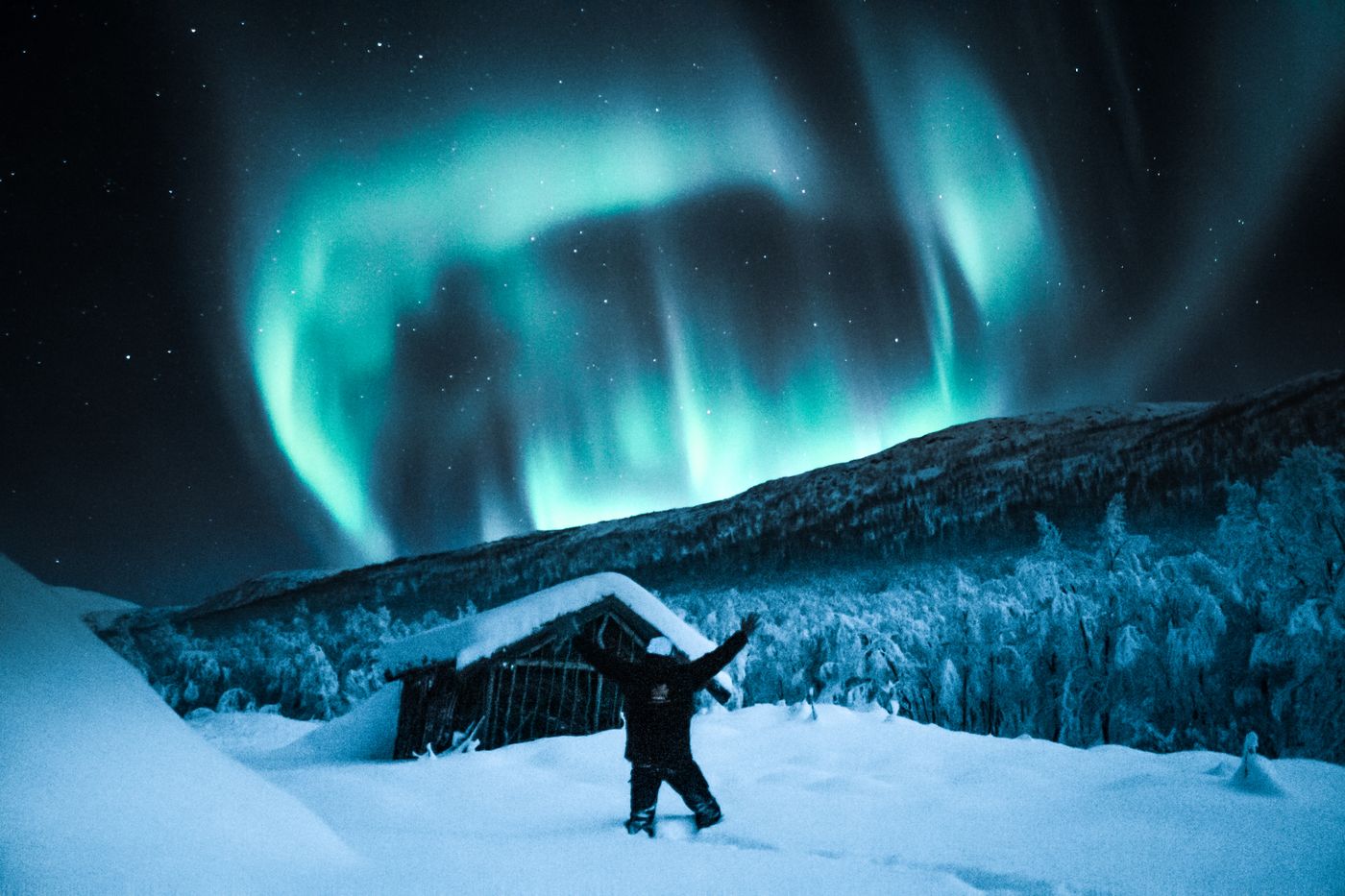 Aurora over a snow-covered cabin — photo by Tobias Bjørkli on Pexels