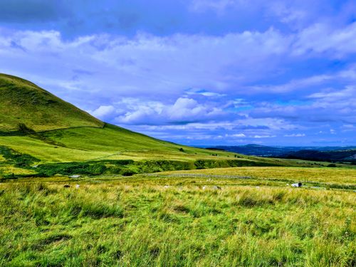 Free Idyllic view of rolling green hills under a vibrant blue sky, perfect for outdoor and nature themes. Stock Photo