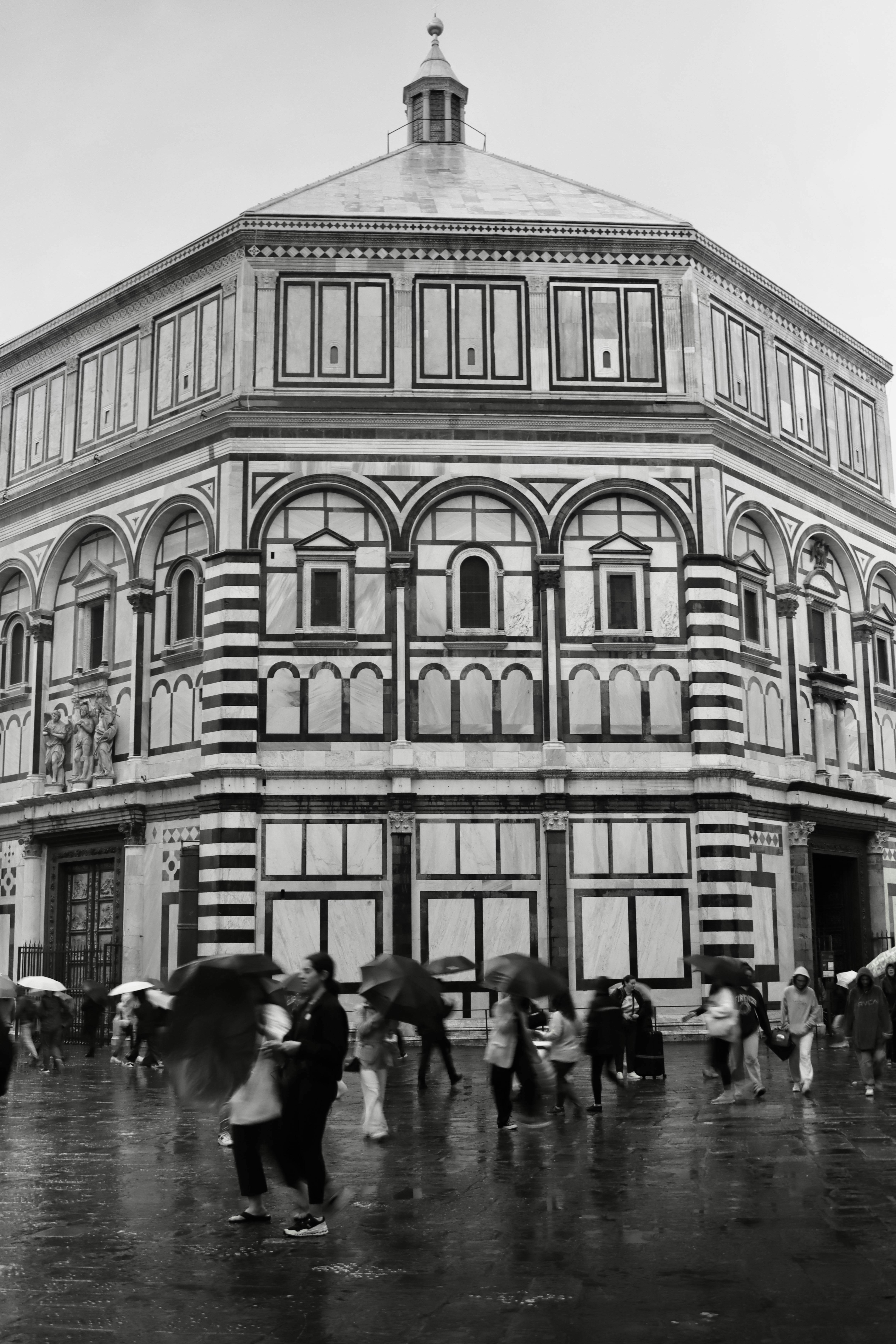 Monochrome view of Florence Baptistery with people in the rain. Iconic Italian architecture.