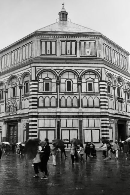 Monochrome view of Florence Baptistery with people in the rain. Iconic Italian architecture.