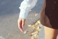 阳光明媚的日子里，一个穿着黑色裙子和白色衬衫的女人走在外面