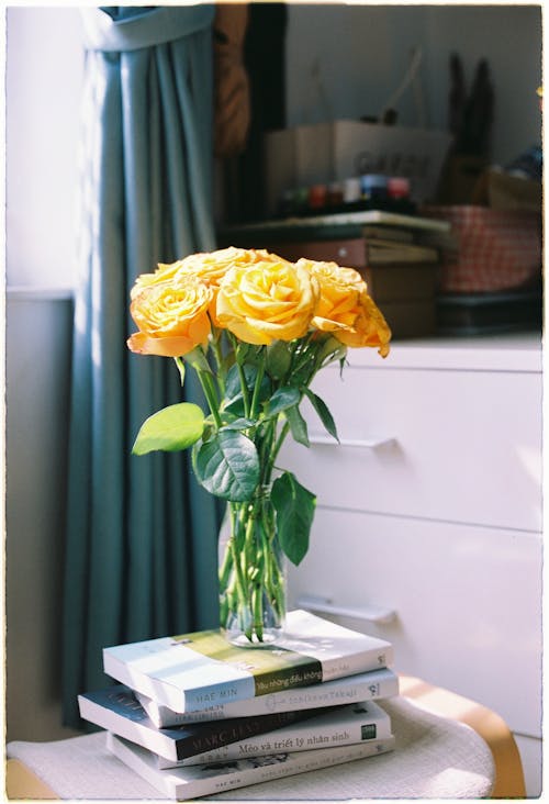 A Bouquet of Yellow Roses in a Vase on a Pile of Books