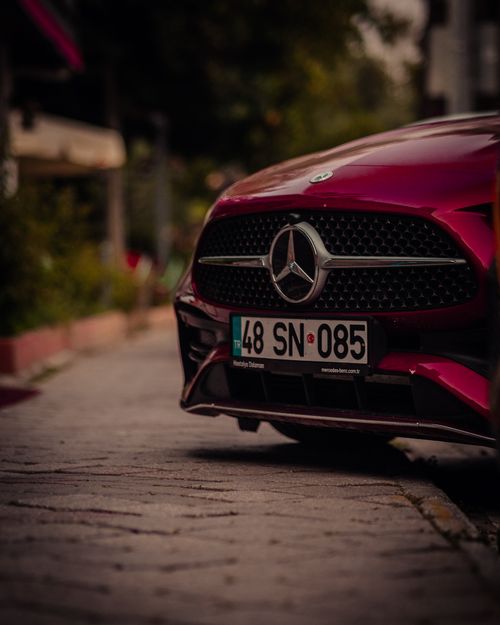 Free Detailed view of a modern Mercedes-Benz grille parked on a sidewalk. Features sleek design and urban background. Stock Photo