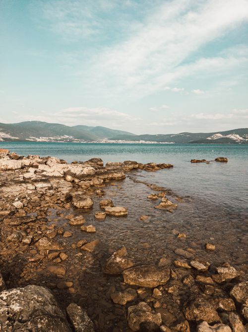 Free Tranquil seaside view with rocky shore and clear blue ocean under a bright sky. Stock Photo