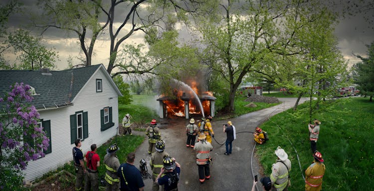 Squad Extinguishing A Burning Garage And A Group Of Watching Firefighters 