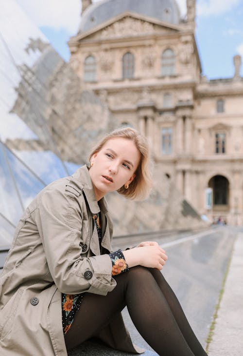 Young Woman Sitting in front of the Louvre Pyramid, Paris, France 