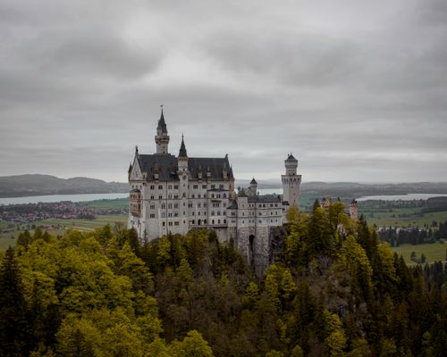 Free A stunning view of Neuschwanstein Castle amid vibrant greenery during summer in Schwangau, Germany. Stock Photo