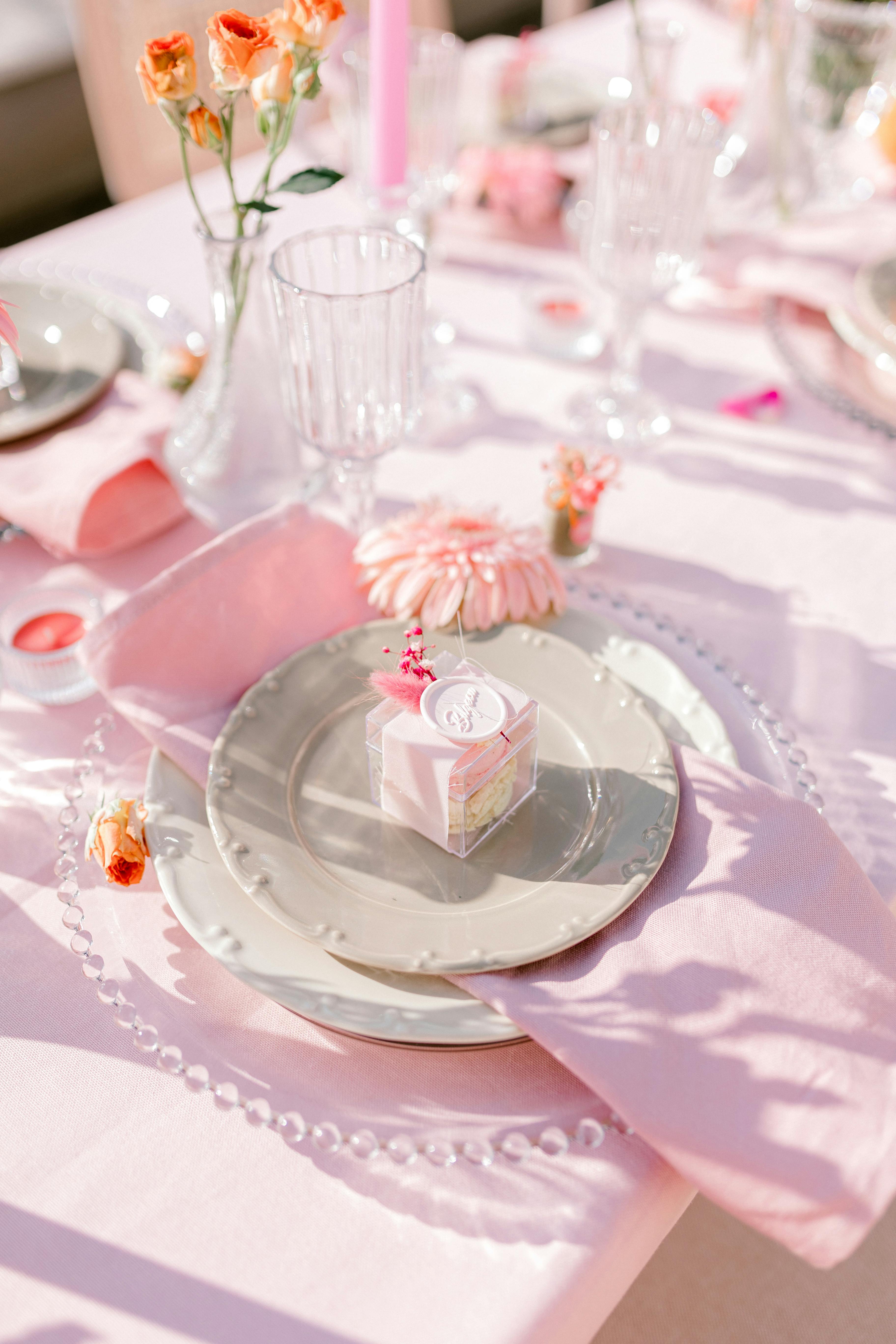Charming pink-themed table setting with flowers and elegant dishware for a special occasion.