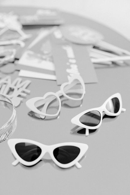 Stylish black and white image of sunglasses and accessories arranged artistically on a surface.