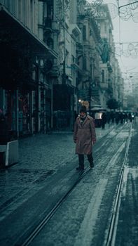 A man walks alone on a rainy winter street in Istanbul, Türkiye, capturing urban life.