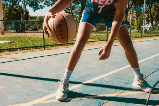 Young athlete playing basketball on an outdoor court in summer.