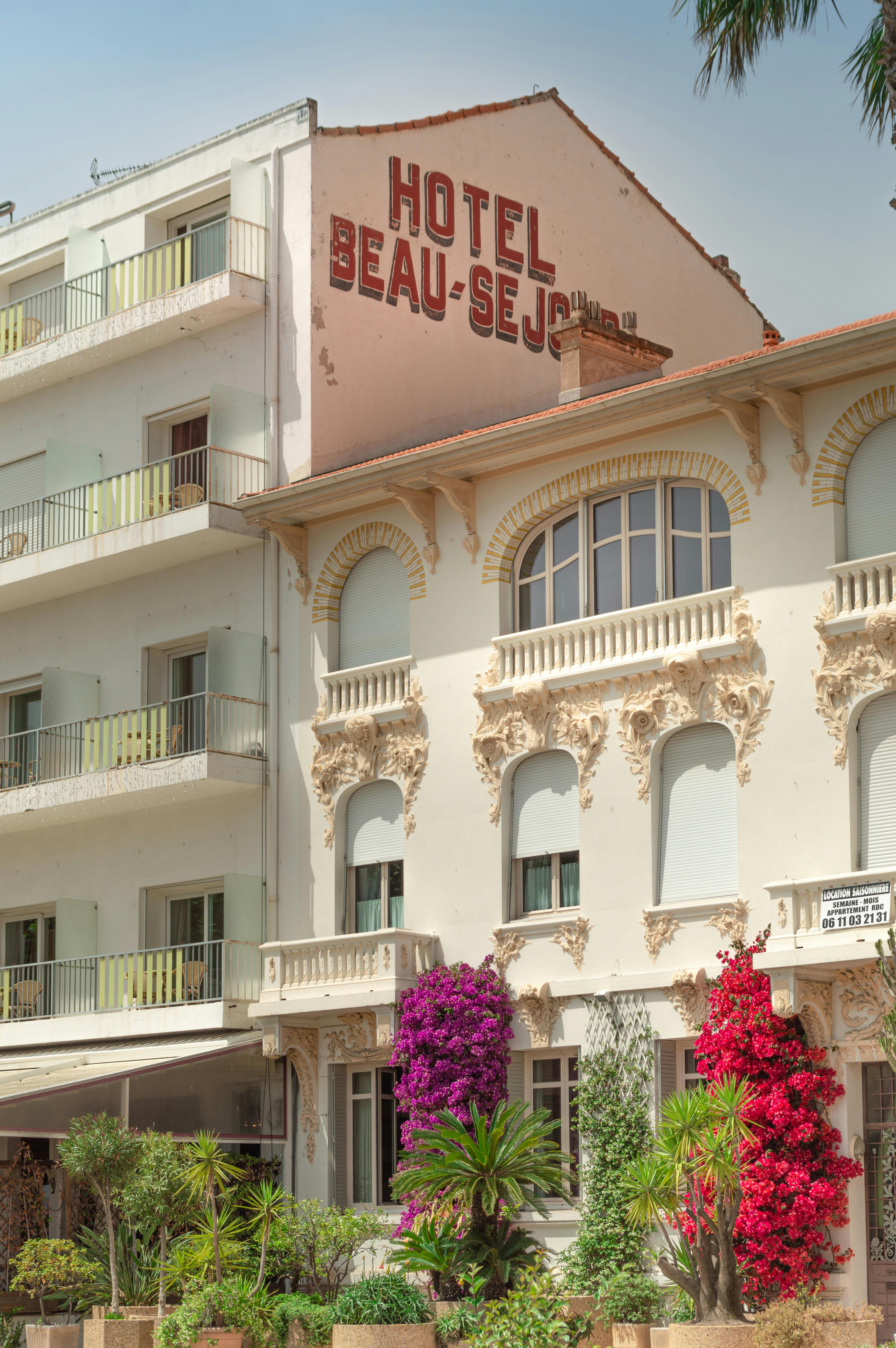 Elegant hotel facade adorned with blooming flowers and intricate architecture under sunny skies.