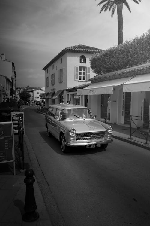 Black and White Shot of a Vintage Car on a Tropical Town Street