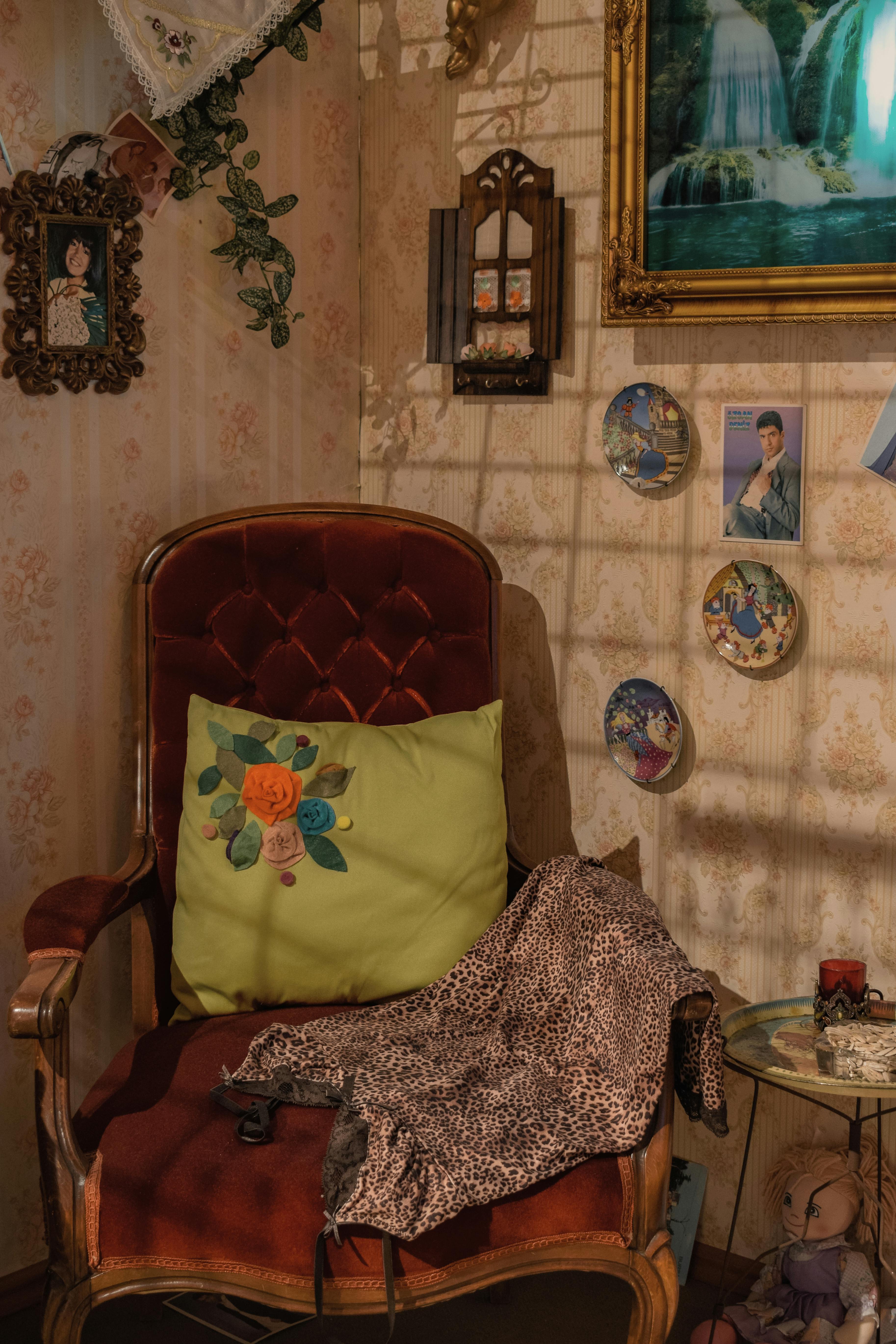 Free A vintage corner featuring a plush armchair, decorative pillows, and framed art. Stock Photo