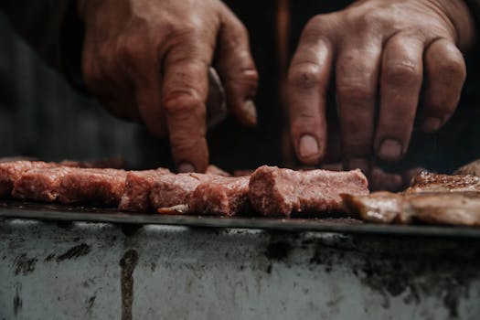 A chef's hands closely grilling traditional Serbian meat in an outdoor setting. 