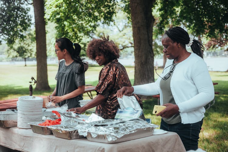 Three Women Catering Food In A Park