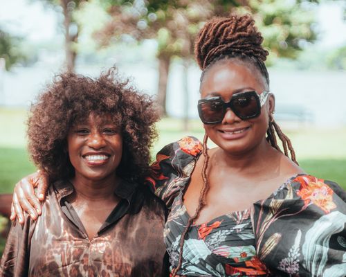 Free Smiling friends in colorful attire enjoying a sunny day in the park. Stock Photo