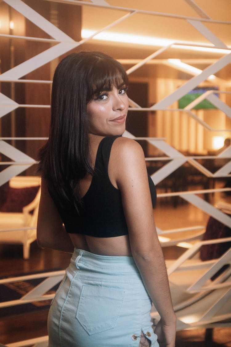 Young Woman In Blue Denim Skirt And Black Crop Tank Top Looking Over Her Shoulder